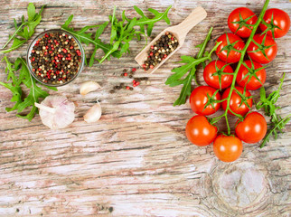 Horizontal food banner with cherry tomatoes, fresh arugula, garlic and peppercorns on wooden background. Empty space for text.