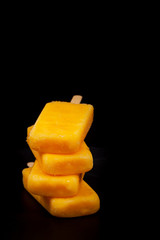 Fototapeta na wymiar Pineapple, Apricot and Mango Popsicles on black background. Selective focus.