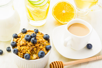 Breakfast with detox fresh water, granola, honey, coffee and milk on white table