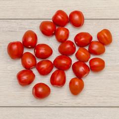 Lots of tomatoes on a wooden table, top view