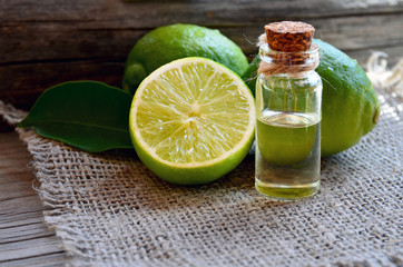 Lime essential oil in a glass bottle with fresh lime fruits.Lime oil for spa,aromatherapy and bodycare.Extract oil of lime.Selective focus. © svf74