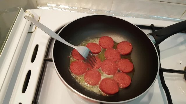 Turkish sausage - sucuk - cooking with butter on a pan over cooker. 