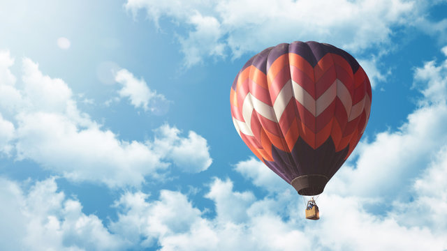 Heißluftballon fliegt vor blauem bewölkten Himmel bei Sonnenuntergang