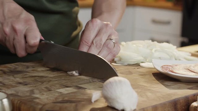 A Woman ina kitchen rolls and slices pancetta bacon with a chefs knife. hot with a RED Dragon digital cinema camera.