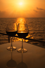 Glasses, red wine and tropical sunset with sea background, nobody.
