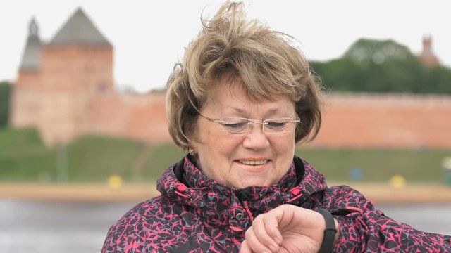Black smartband. Outdoors adult woman looks at the results of physical activity using the smart fitness tracker then shows a thumbs up sign. Slow motion