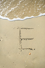 E Letter drawn on the sand beach
