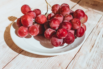 Fresh red grapes in a plate on wooden table, flatlay