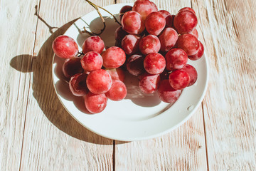 Fresh red grapes in a plate on wooden table, flatlay
