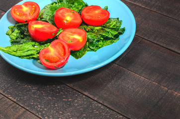 Tomatoes and greens spinach on a blue plate