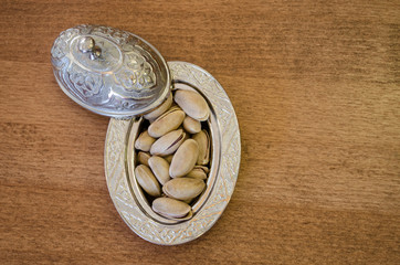 Fototapeta na wymiar Copper bowl on a wooden table with pistachio