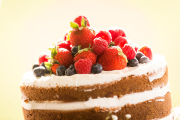 Close up of a homemade wedding cake topped with raspberries, strawberries, and blueberries.