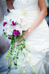 Beautiful fit bride with white and purple bouquet.