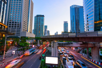 Photo of commercial office buildings exterior. Night view at bottom skyscrapers with blank bill board and light of traffic rush in Bangkok