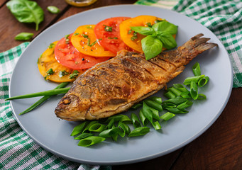 Fried fish carp and fresh vegetable salad on wooden background.