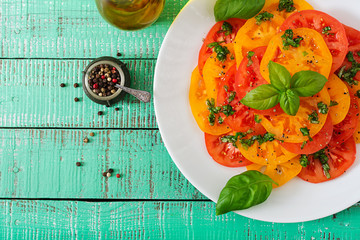 Salad of yellow and red tomato with Basil pesto on a light background. Flat lay. Top view