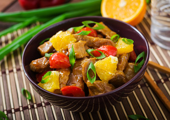 Veal fillet - stir fry with oranges and paprika in sweet and sour sauce on a wooden background.