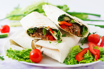 Burritos wraps with minced beef and vegetables on a light background.