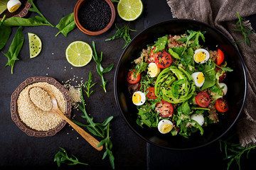 Diet menu. Healthy salad of fresh vegetables - tomatoes, avocado, arugula, egg, spinach and quinoa on a bowl. Flat lay. Top view.