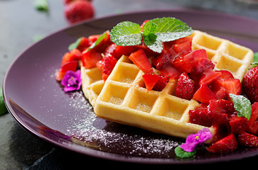 Belgium wafers with strawberries and syrup on a plate.