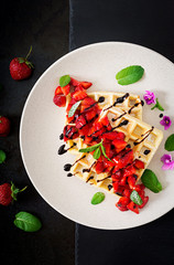 Belgium wafers with strawberries, chocolate and syrup on a plate. Flat lay. Top view.