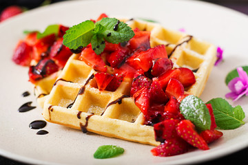 Belgium wafers with strawberries, chocolate and syrup on a plate.