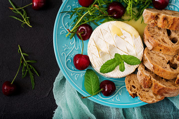 Baked Camembert cheese, toast and arugula salad with  sweet cherries. Flat lay. Top view