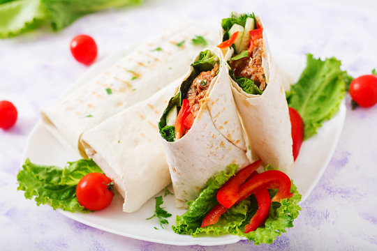 Burritos wraps with minced beef and vegetables on a light background.
