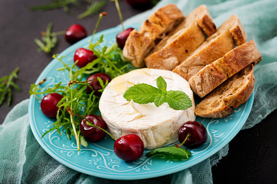 Baked Camembert cheese, toast and arugula salad with  sweet cherries.