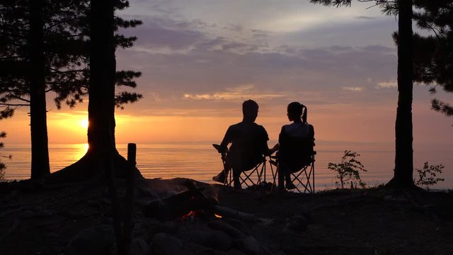 Couple is Sitting near Campfire at Night.