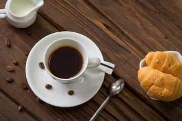 Morning coffee in a cup on a table with croissants and milk
