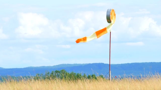 Wind sock fly. Summer hot day on privat sporty airport with abandoned windsock, wind is blowing and windsock is lazy  moving