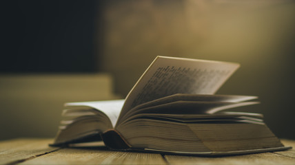 opened book on wooden table, shallow depth of field and cinema color effect