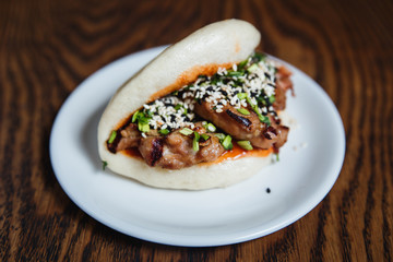 Asian gua bao with grilled chicken, teriyaki sauce, green onion and sesame seeds. Selective focus, small depth of field.