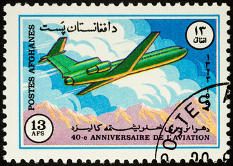 Passenger aircraft over mountains on postage stamp