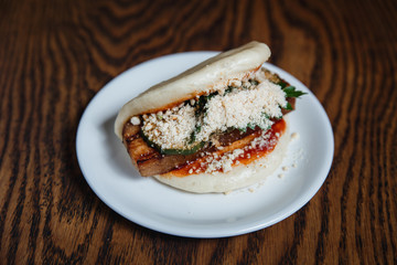 Asian gua bao with grilled brisket, teriyaki sauce, vegetables and nuts. Selective focus, small depth of field.