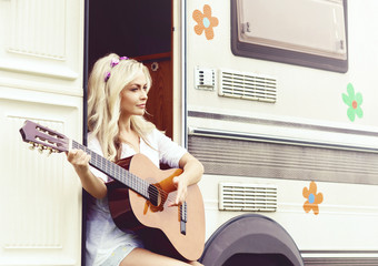 Young hippie girl playing guitar outdoors at summer. Holiday, journey, vacation concept.