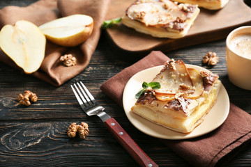 Plate with delicious pastry and fork on wooden table