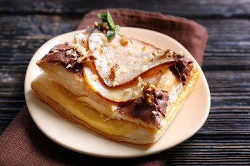 Tasty puff pastry with pear, chocolate and nuts on plate