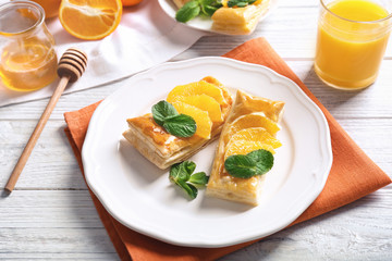 Tasty puff pastry dessert with orange and mint on served table