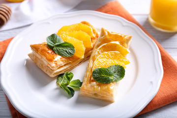 Tasty puff pastry dessert with orange and mint on served table