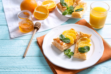 Tasty puff pastry dessert with orange and mint on served table