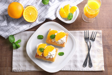 Tasty puff pastry dessert with orange and whipped cream on plate