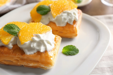 Tasty puff pastry dessert with orange and whipped cream on plate