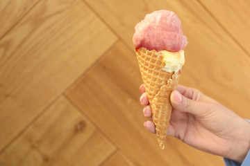 Woman holding portion of ice cream on wooden background