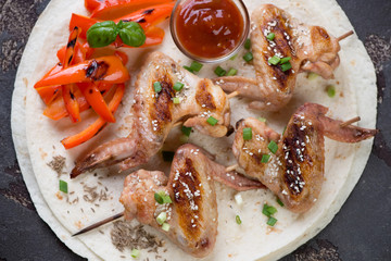 Tortilla bread with grilled chicken wings skewers, above view, horizontal shot