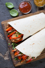 Tortilla bread filled with bbq chicken meat and vegetables, above view, vertical shot