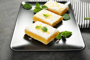 Plate with delicious lemon pie bars on table