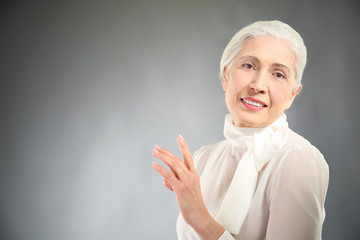 Beautiful elegant elderly woman on gray background