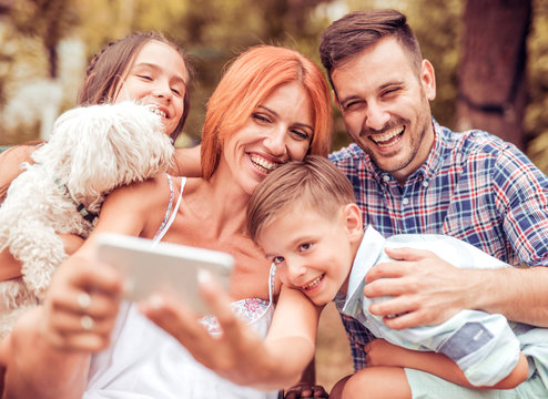 Happy family with dog taking selfie by smart phone in the park